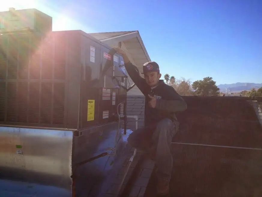 HVAC technician performing HVAC Inspection on a rooftop unit in Alma