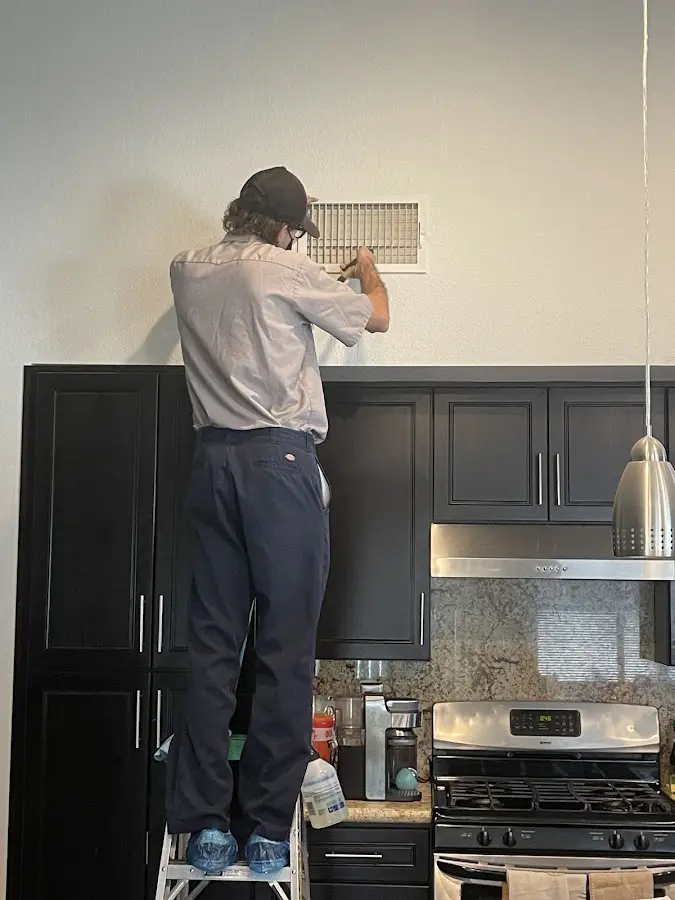 Technician inspecting an air vent during HVAC service in Alma